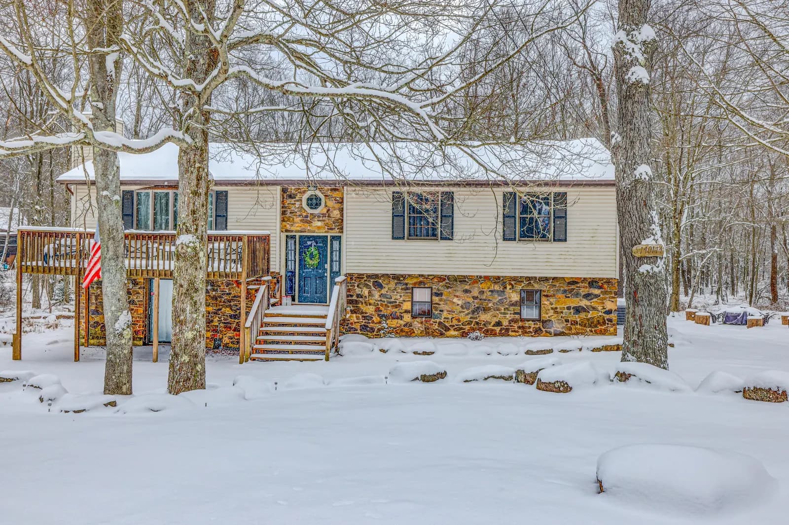 The Arrowhead Lake house in the snow, framed by bare winter trees