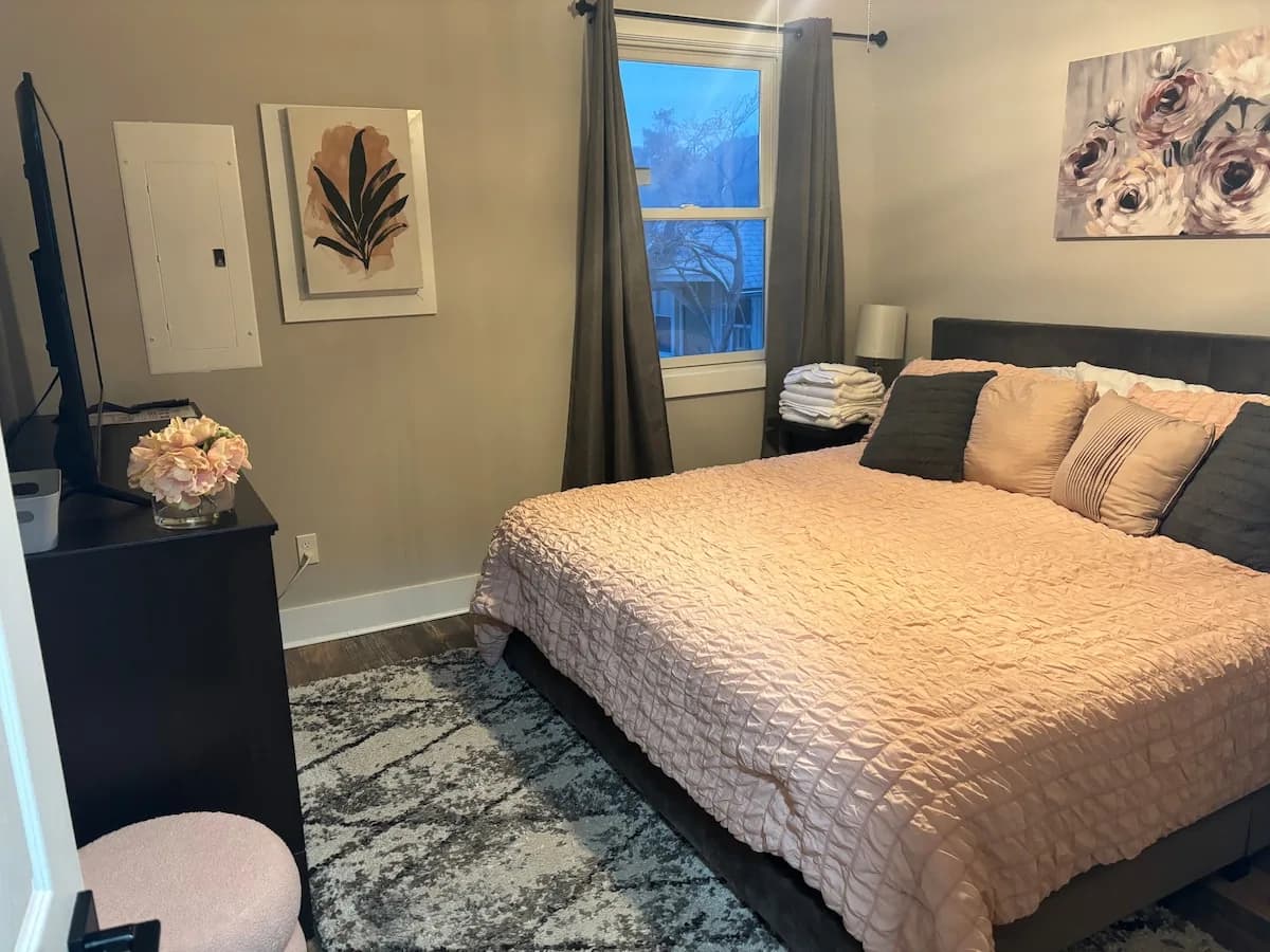 Calm guest bedroom with a blush bed and blackout curtains