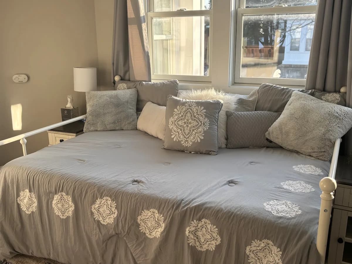 Sunlit guest bedroom with daybed and layered linens