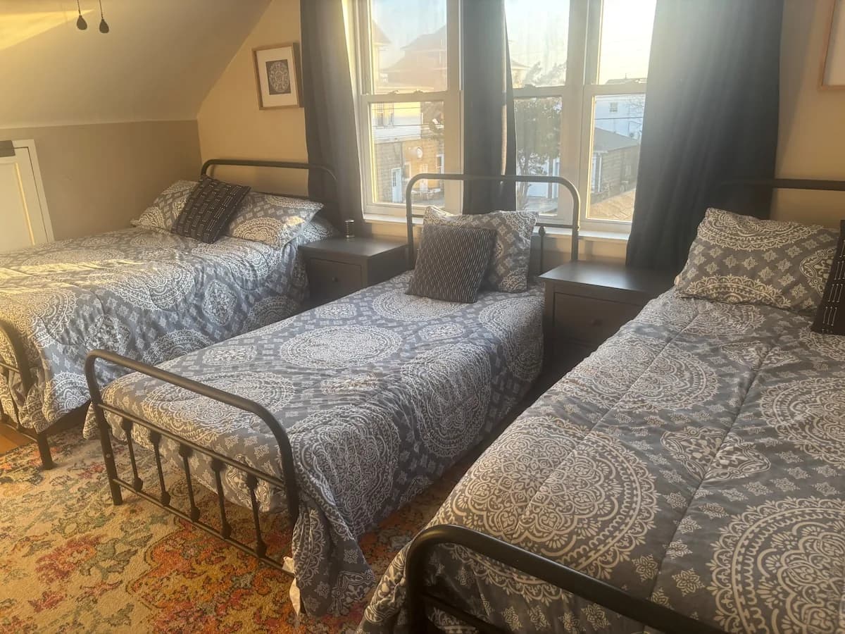 Sunlit upstairs bedroom with two iron-frame beds