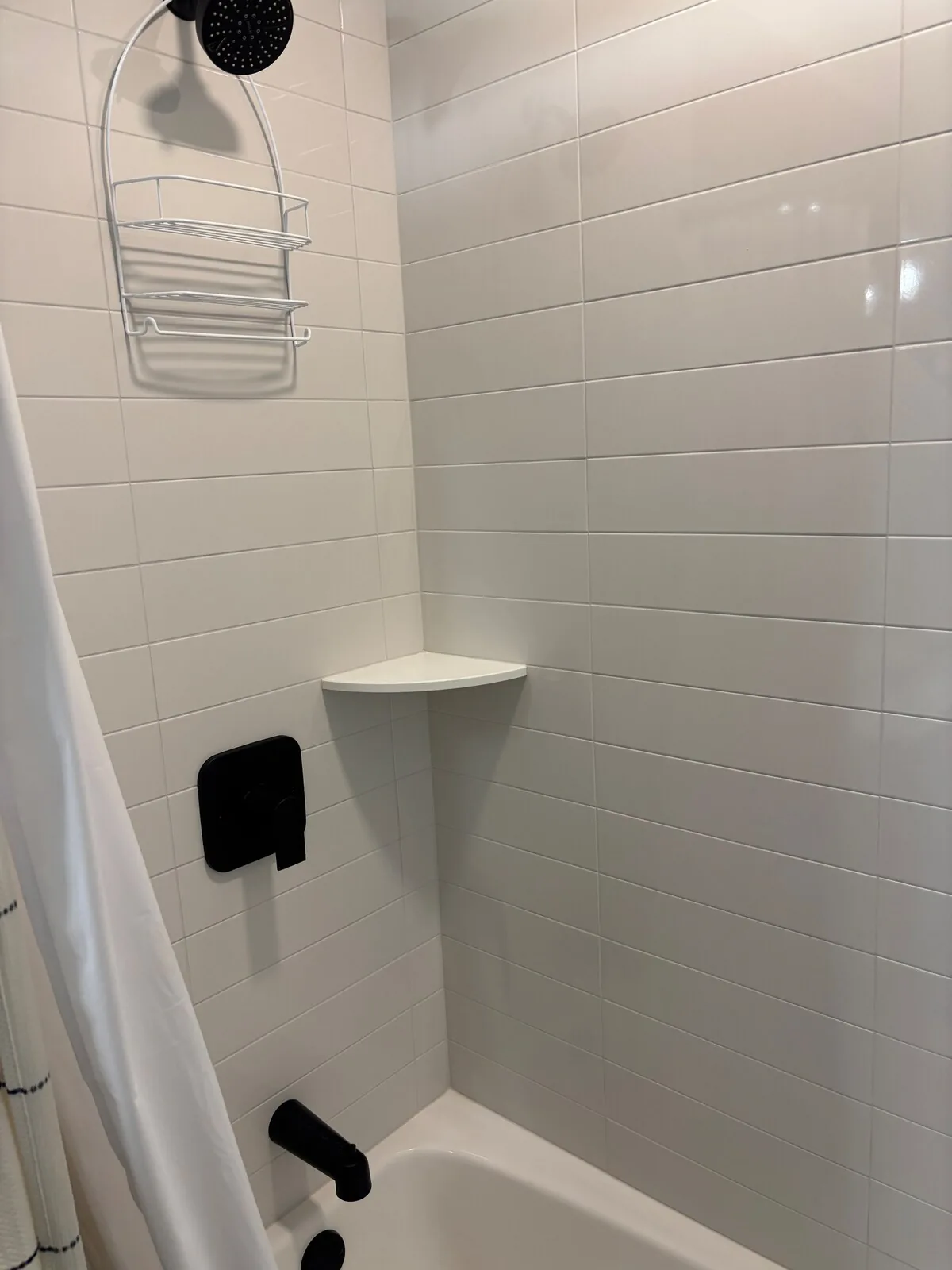 Bright tiled shower with built-in corner shelf