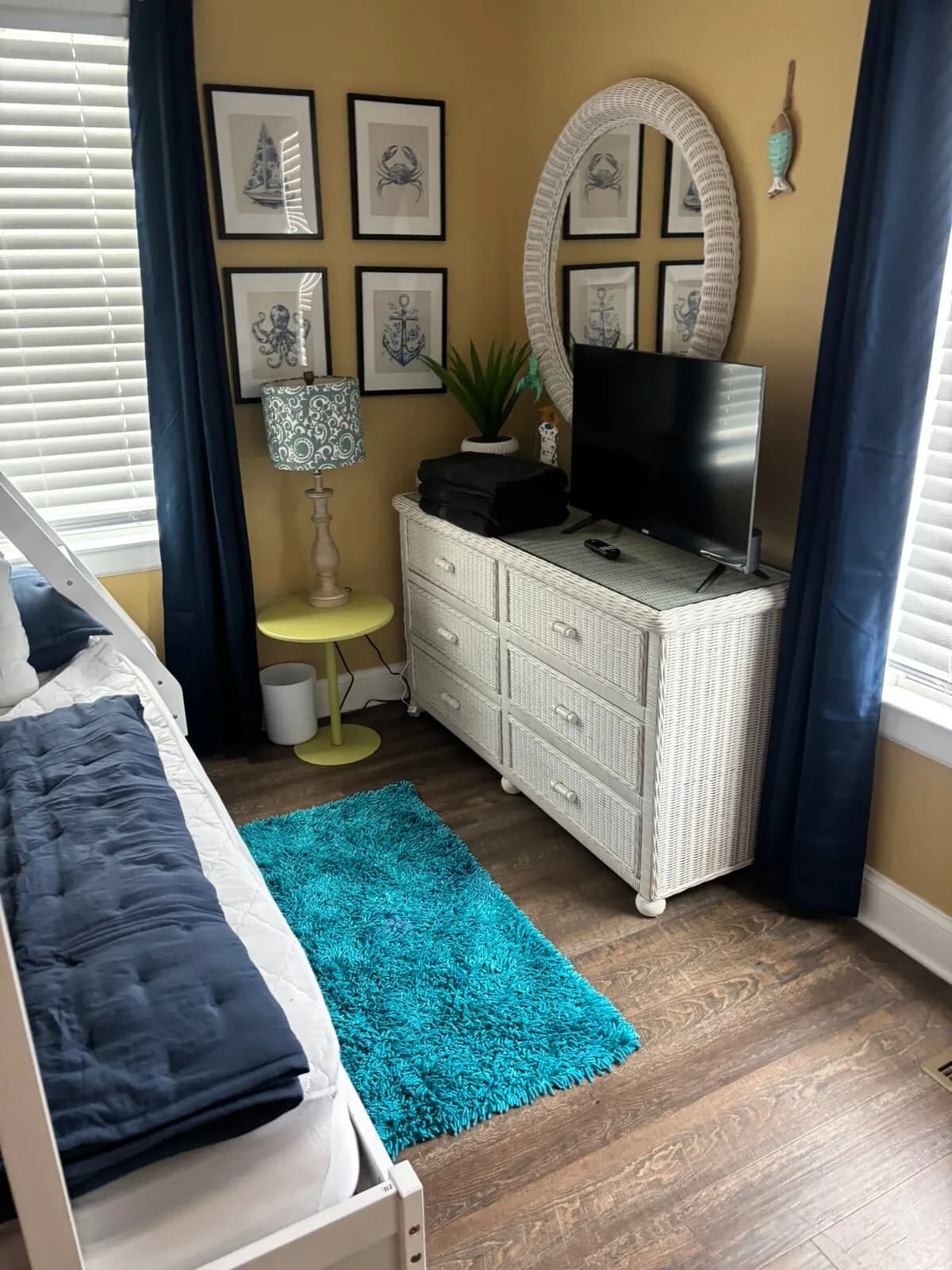 Blue bedroom with dresser, television, and blackout curtains