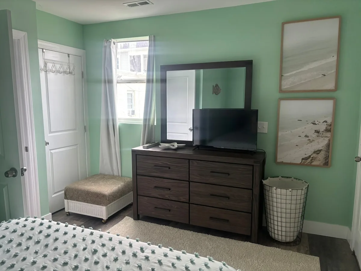 Mint guest room with dresser and television